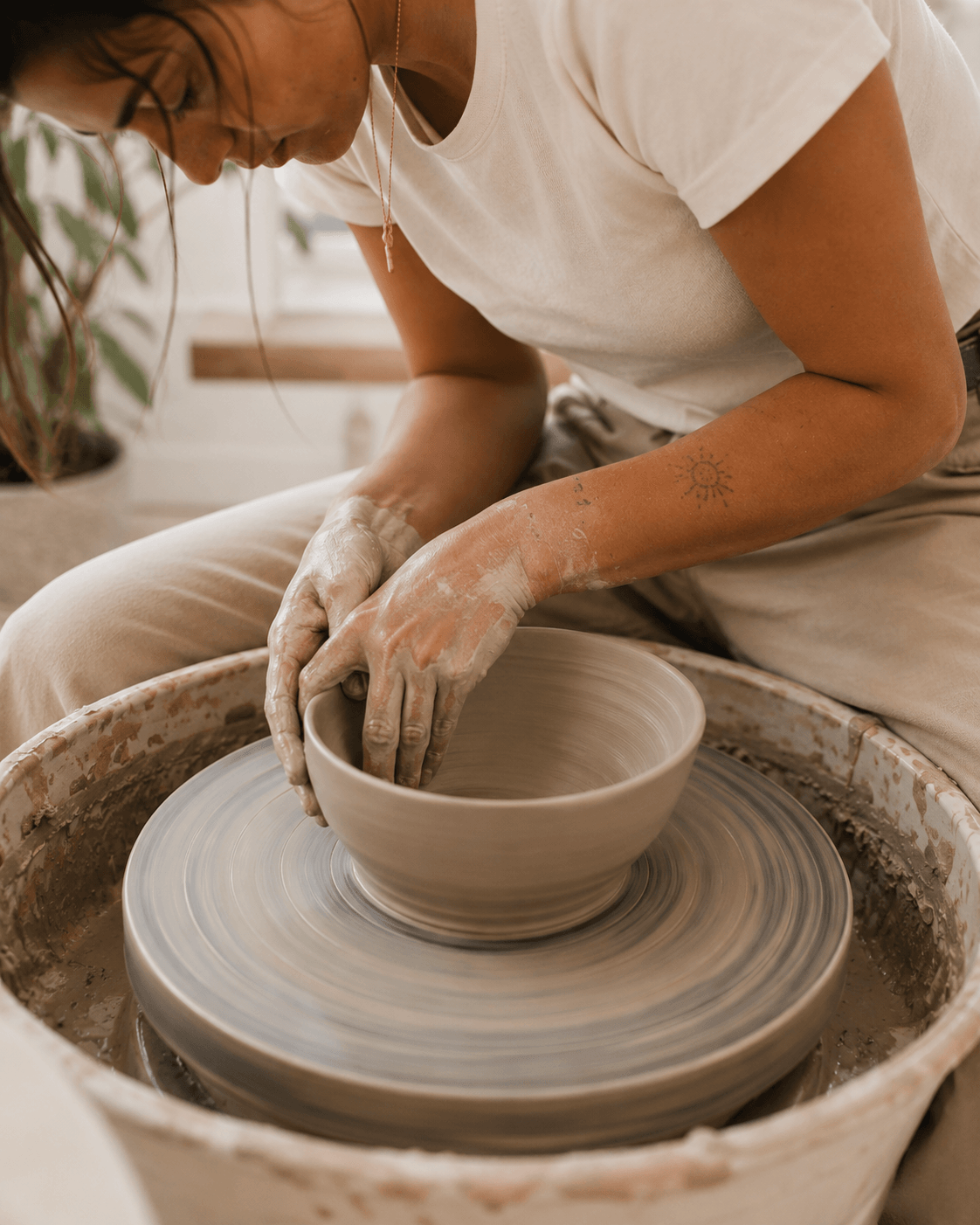 Close-up of hands shaping a bowl on the pottery wheel